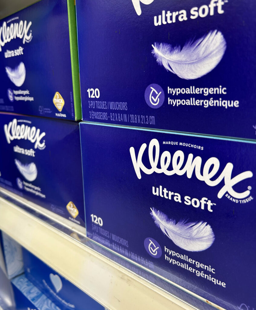 blue boxes of Kleenex brand tissues stacked on store shelf