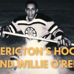 yellow text "FREDERICTON"S HOCKEY LEGEND WILLIE O'REE" over black and white image of hockey player Willie O'Ree holding a hockey stick and wearing a Boston Bruins Jersey.
