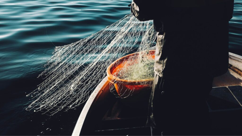 image of lower half of fisherman holding fishing net above water