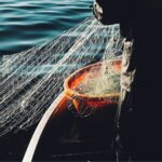 image of lower half of fisherman holding fishing net above water