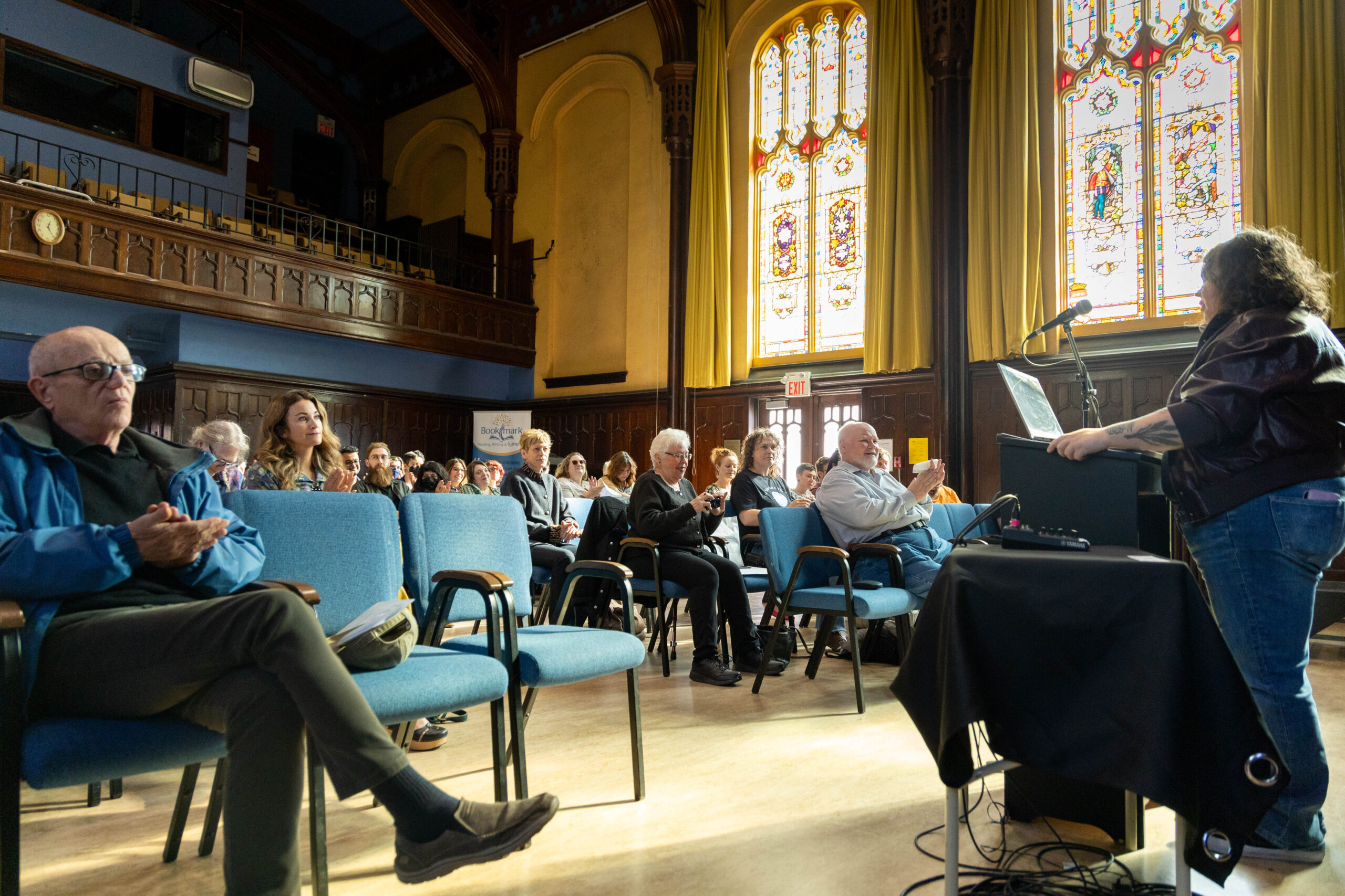 Jamie Kitts reading in front of a crowd of poetry weekend attendees in Memorial Hall.